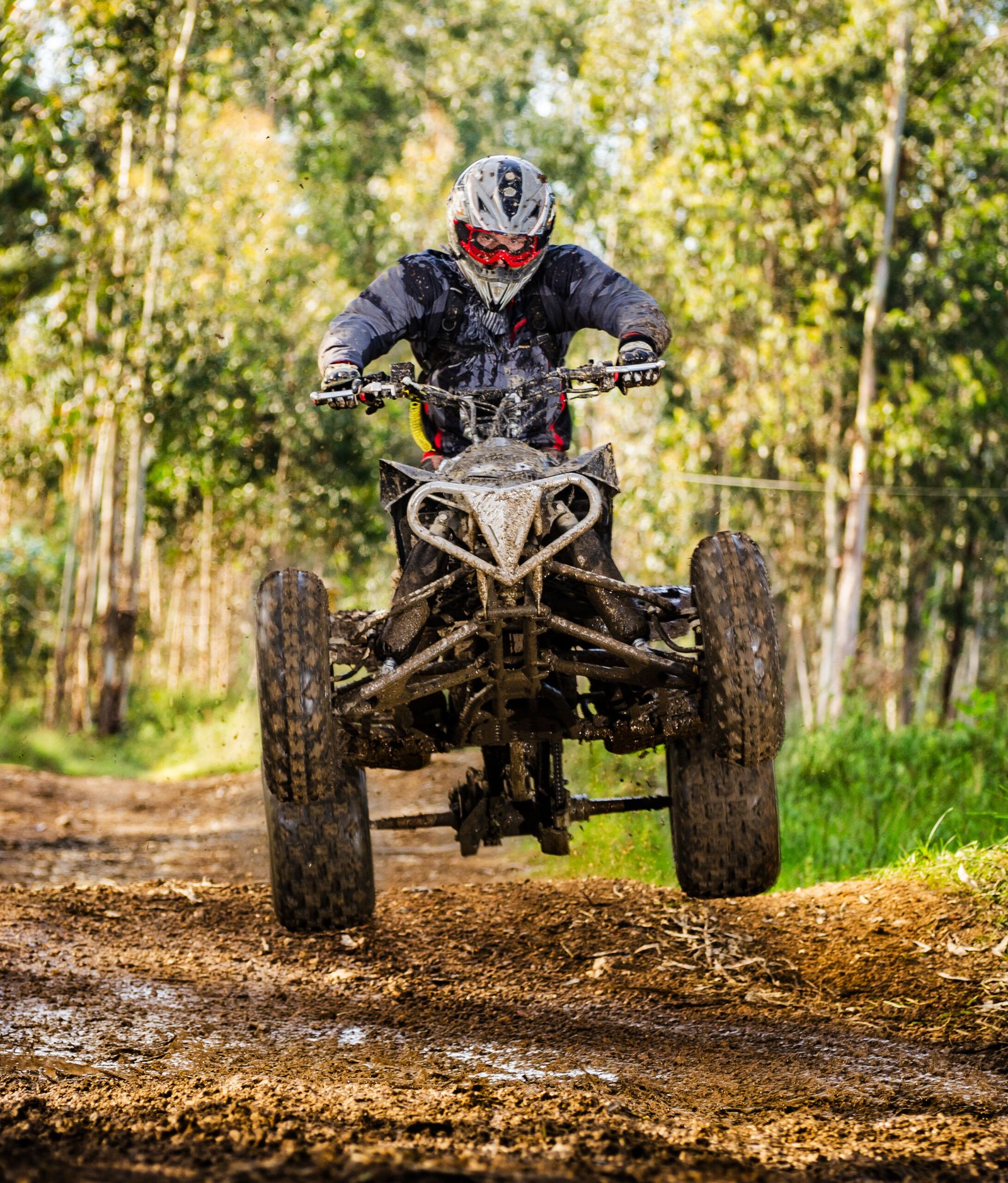 Quad rider jumping on a forest trail.